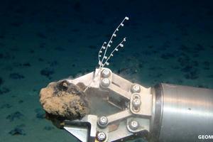 A mechanical claw holds a polymetallic nodule, one of several seafloor sources of critical minerals. ROV-Team/GEOMAR via Wikimedia, CC BY