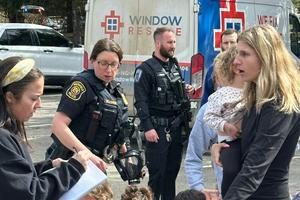 A woman gathers children as law enforcement responds at a Michigan synagogue after an assailant drove a vehicle into the building on March 12, 2026.  AP Photo/Corey Williams