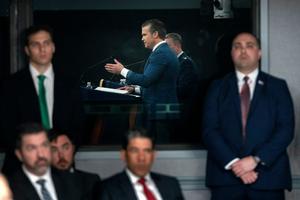 Staff members watch as Defense Secretary Pete Hegseth speaks during a press briefing at the Pentagon on March 2, 2026.  AP Photo/Mark Schiefelbein