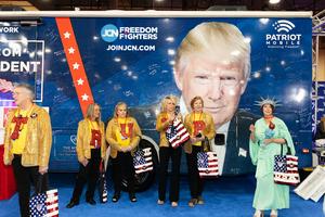Attendees wearing MAGA merch stand next to an image of Trump at the Conservative Political Action Conference in Grapevine, Texas, on March 25, 2026. Leandro Lozada AFP/Getty Images