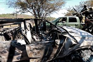 Members of the army onboard a truck are seen next to a burned car used to block roads while Mexican drug lord 