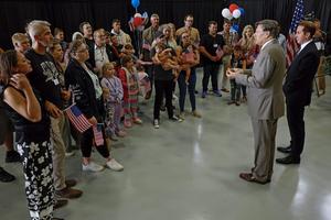Newly arrived South Africans listen to U.S. Deputy Secretary of State Christopher Landau deliver welcome statements in a hangar near Washington Dulles International Airport on May 12, 2025.  Chip Somodevilla/Getty Images
