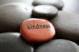 The word Kindness carved in goldstone resting on river rocks. Dreamstime/TCA