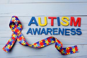 World Autism awareness and pride day or month with Puzzle pattern ribbon on blue wooden background. Dreamstime/TCA