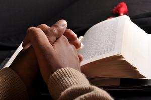Praying hands on Bible. Dreamstime/TCA