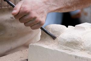 Close-up of a sculptor at work at work on a sand-tone block. Dreamstime/TCA