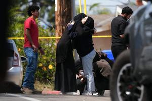 People comfort one another near the scene of a shooting outside the Islamic Center of San Diego on May 18, 2026, in San Diego.  AP Photo/Gregory Bull