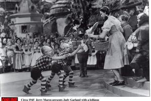 1939: Jerry Maren, playing a Lollipop Guild Member, presents Judy Garland with a lollipop in the film 