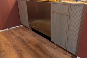There are three cabinets in this photo. A sink base is to the left of the refrigerator/freezer. A trash-can cabinet and small slide-out shelf cabinet are to the right. This is the bar area of a basement speakeasy. (Tim Carter/Tribune Content Agency/TNS)