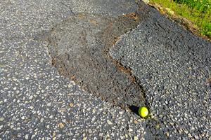 This asphalt patch was installed two years ago. It was a product in a bag bought from a home center. It started to fail within one year. The golf ball is for scale. (Tim Carter/Tribune Content Agency/TNS)