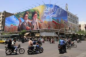 People ride motorcycles past a large billboard in central Tehran on June 8, 2026. Atta Kenare/AFP via Getty Images