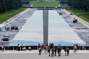WASHINGTON, DC - JUNE 6: People walk past the Reflecting Pool on the National Mall on June 6, 2026 in Washington, DC. The Trump Administration has repainted and cleaned the Reflecting Pool ahead of the country's 250th anniversary next month. (Photo by Aaron Schwartz/Getty Images)