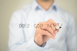 Does God Exist, man writing on transparent screen. Dreamstime/TCA