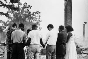 Members of the Student Nonviolent Coordinating Committee pray beside the ruins of a burned church near Dawson, Ga., in 1962. Bettmann Archive/Getty Images