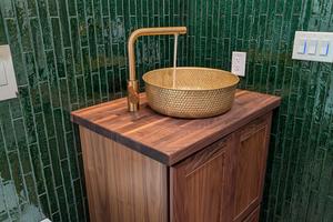 This solid-brass vessel sink is installed on a solid walnut butcher block top. The crackled green subway tile walls create a dramatic look. (Tim Carter/Tribune Content Agency/TNS)
