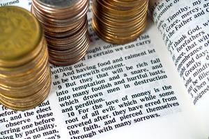 I Timothy 6:10 Love of Money 1. A Bible opened to I Timothy 6:10 with coins around it. Dreamstime/TCA